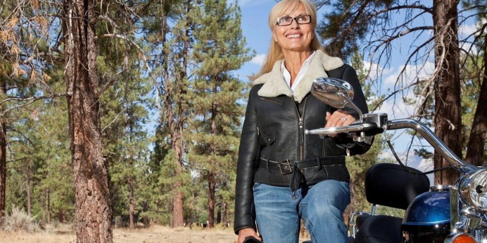 Senior woman poses with motorcycle in forest